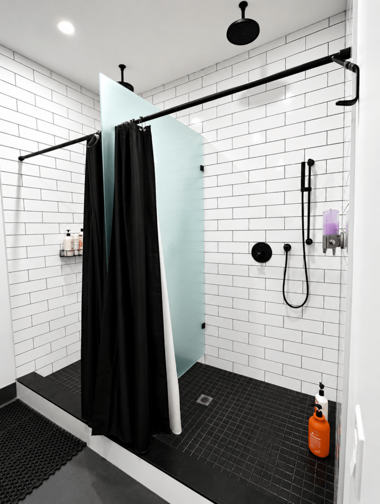 Modern, clean shower facilities with private stalls at Hitters Fight Club Toronto featuring rainfall showers, frosted glass dividers, and premium amenities.